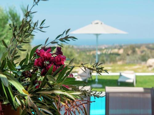 a plant with pink flowers next to a pool at Villa in Arkadi with Pool near the Sea in Kiriánna