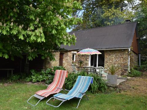 two chairs and an umbrella in front of a house at Lovely holiday home with garden terrace and fantastic view in Guilberville in Fourneaux