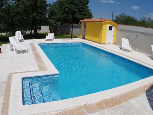 a swimming pool with chairs and a yellow house at Detached house at country side fenced privat garden Ideal for 2 fam Free WiFi in Vodnjan