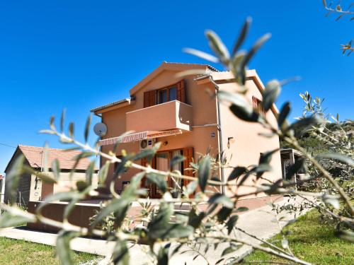 a house in the background with trees in the foreground at Serene Holiday Home in Veli I with Fenced Garden in Veli Iž