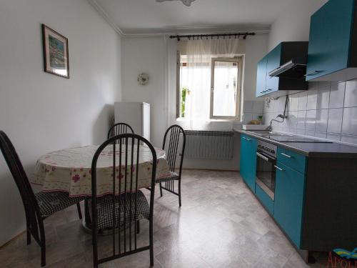 eine Küche mit blauen Schränken sowie einem Tisch und Stühlen in der Unterkunft Charming Apartment in Vantacici amid the Sea in Dragozetići
