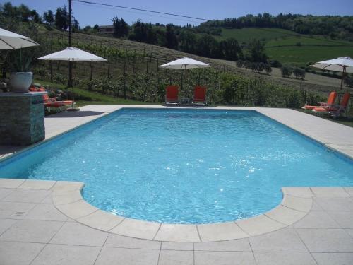 a large swimming pool with two chairs and umbrellas at Residence Villa degli Ulivi in Bertinoro