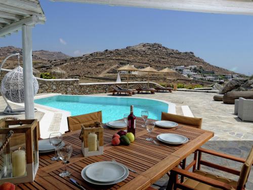 カラファティスにあるBeautiful large luxury villa in Mykonosの木製テーブル(プールサイドの果物プレート付)