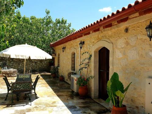 eine Terrasse mit einem Tisch, Stühlen und einem Sonnenschirm in der Unterkunft Quaint Holiday Home in Pasalites in Pasalítai