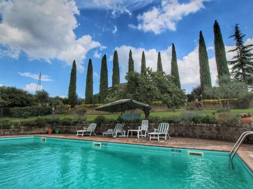 a swimming pool with chairs and an umbrella next to a garden at Belvilla by OYO Villa La Palazzeta in Ficulle