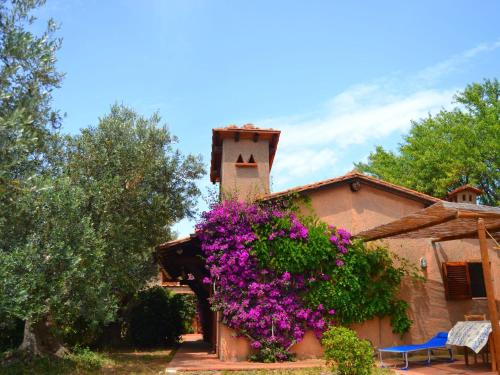 un edificio con flores púrpuras a su lado en Belvilla by OYO Comfy Holiday Home with Garden, en Monte Argentario