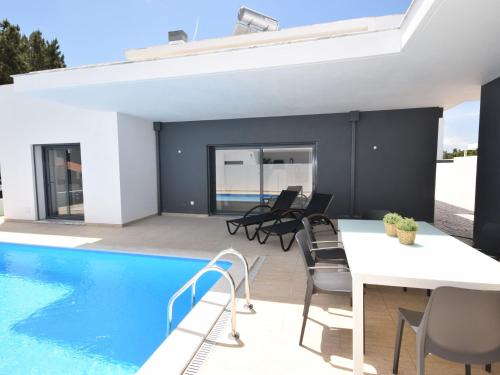a patio with a white table and chairs next to a swimming pool at Modern villa with private pool near the beautiful beach of Foz de Arelho in Nadadouro