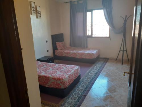 Habitación con 2 camas, silla y ventana en Appartement Chham, en Marrakech