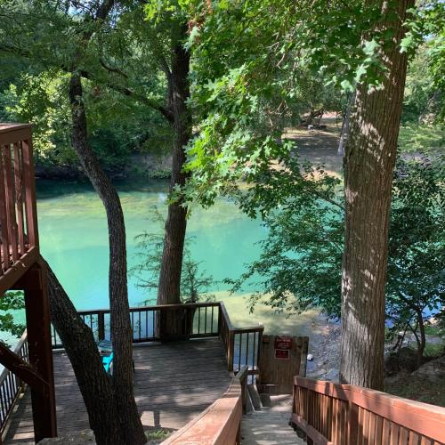 a wooden bridge over a river with trees at Lamb's Rest Inn in New Braunfels