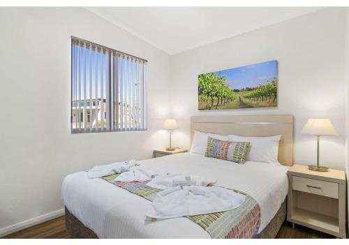 a bedroom with a bed with white sheets and a window at Discovery Parks - Swan Valley in Caversham