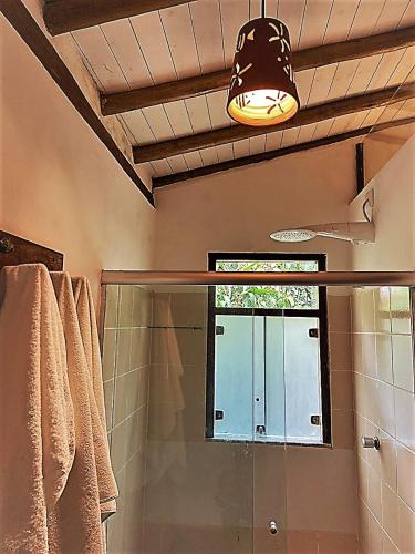 a bathroom with a shower with a glass door and a light at Pousada Big Bambu in Trancoso