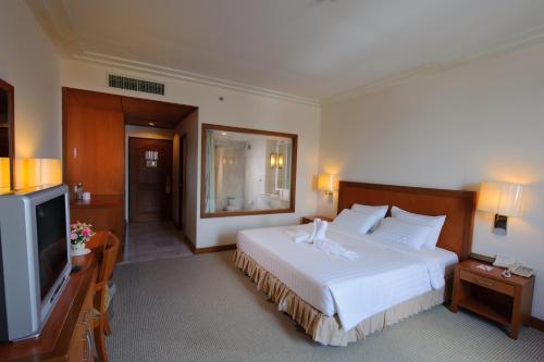 a hotel room with a bed and a flat screen tv at Grand Mandarin Betong Hotel in Betong