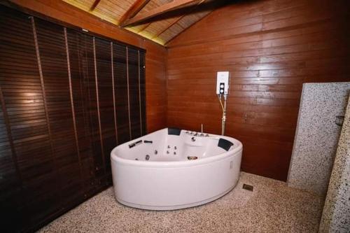 ein Badezimmer mit einer weißen Badewanne an einer Holzwand in der Unterkunft Perak Agrotourism Resort in Tanjung Tualang