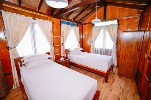 2 Betten in einem Zimmer mit Holzwänden und Fenstern in der Unterkunft Perak Agrotourism Resort in Tanjung Tualang