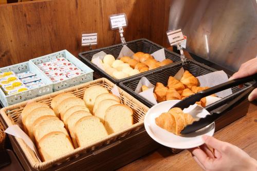 a person holding a plate of bread and pastries at Hotel Sunriver Shimanto in Shimanto