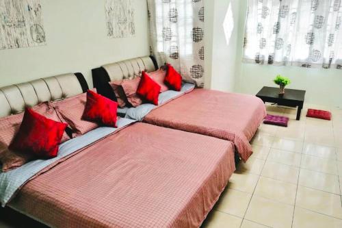two beds with red pillows in a room at LILY VACATION HOME at CAMERON HIGHLANDS - 12 PAX,FREE WiFi w CARPORCH in Tanah Rata