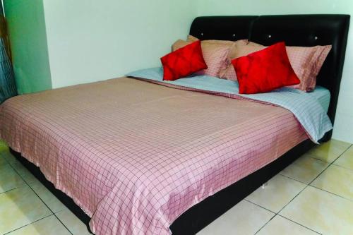a bed with red pillows on top of it at LILY VACATION HOME at CAMERON HIGHLANDS - 12 PAX,FREE WiFi w CARPORCH in Tanah Rata