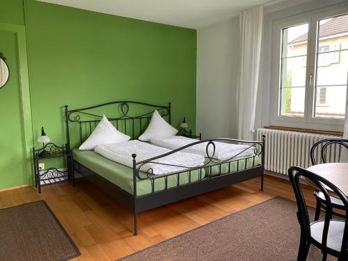 ein grünes Schlafzimmer mit einem Bett und einem Tisch in der Unterkunft BnB Hopfengrün Langenthal in Langenthal