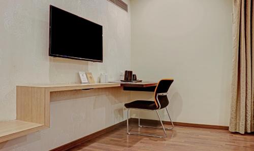 a desk with a chair and a television on a wall at The Onyx Hotel in Jamshedpur