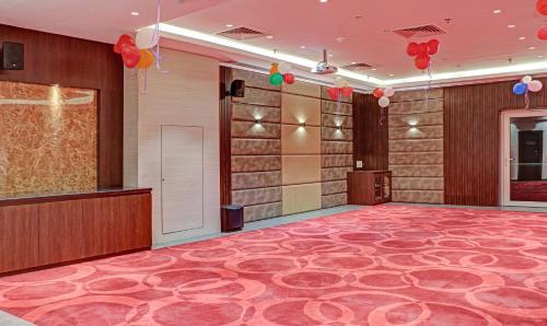 a large room with a red carpeted floor and balloons at The Onyx Hotel in Jamshedpur