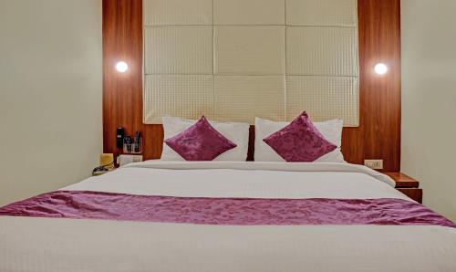 a bedroom with a large bed with purple pillows at The Onyx Hotel in Jamshedpur