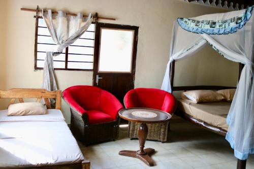 Zimmer mit 2 Betten, 2 Stühlen und einem Tisch in der Unterkunft Room in Guest room - A wonderful Beach property in Diani Beach Kenya - A dream holiday place in Mombasa