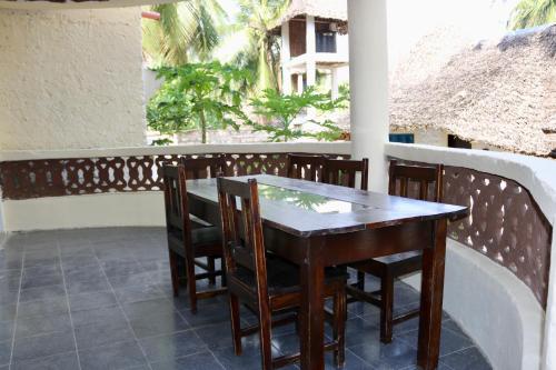 uma mesa de madeira e cadeiras numa varanda em Room in Guest room - A wonderful Beach property in Diani Beach Kenya - A dream holiday place em Mombasa