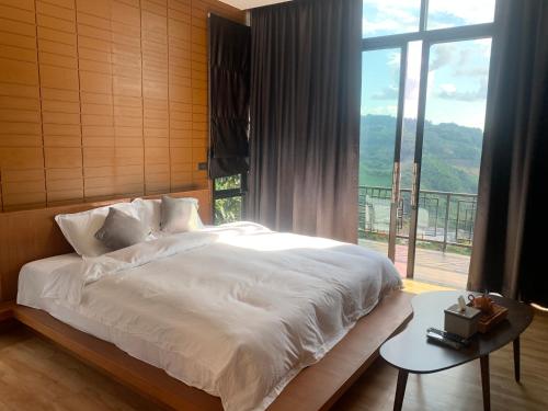 a bedroom with a large bed and a large window at Twins Farm in Mae Salong