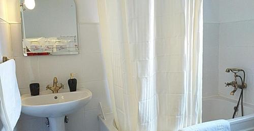 a white bathroom with a sink and a shower at Pensiunea Vila Gabriel in Sinaia
