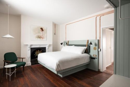 1 dormitorio con 1 cama, 1 silla y chimenea en Warders Hotel Fremantle Markets, en Fremantle