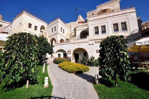 a large white building with a pathway in front of it at Tafoni Houses Cave Hotel in Ortahisar