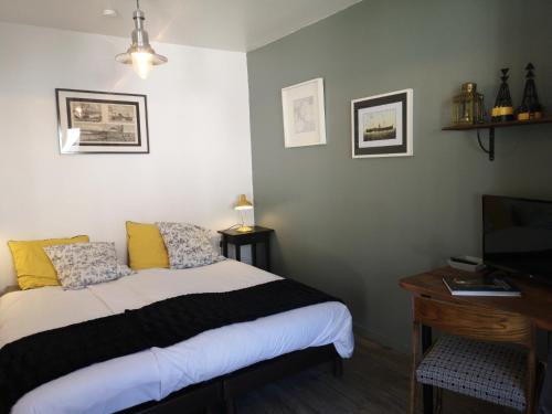a bedroom with a bed and a desk and a television at La Compagnie des 5 Mondes in Saint-Nazaire