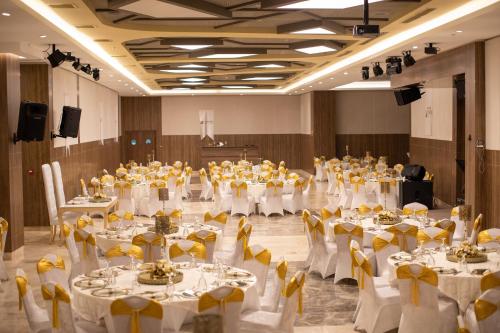 ガジエミル（イズミル）にあるExtenso Hotelの白いテーブルと黄色い椅子が備わる大宴会場