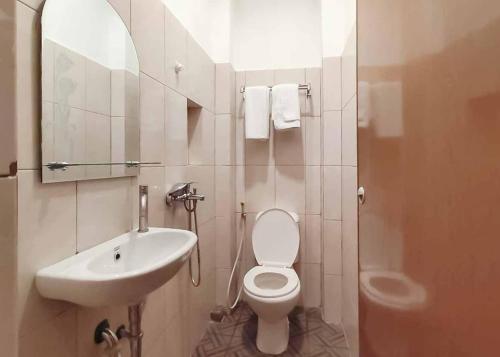 een badkamer met een wastafel, een toilet en een spiegel bij RedDoorz Plus @ Jalan Letda Sujono Medan 2 in Pulauberayan Dadap