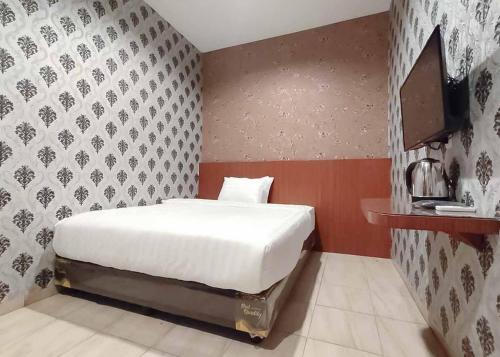 een slaapkamer met een wit bed en een muur bij RedDoorz Plus @ Jalan Letda Sujono Medan 2 in Pulauberayan Dadap