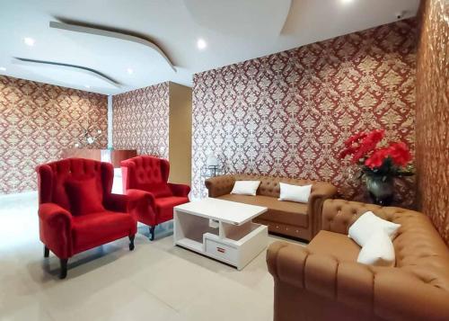 a living room with a couch and two red chairs at RedDoorz Plus @ Jalan Letda Sujono Medan 2 in Pulauberayan Dadap