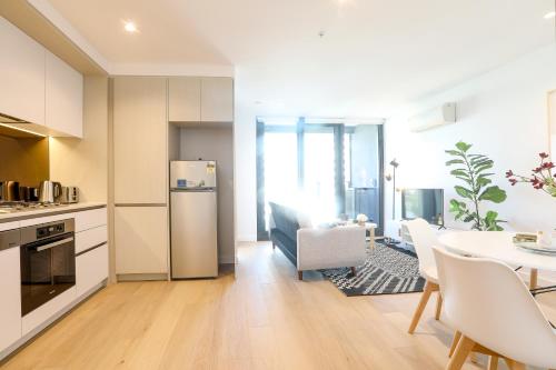 a kitchen and dining room with a table and a refrigerator at KOZYGURU DOCKLANDS MODERN COZY 1 BED ROOM UNIT MELBOURNE VDO628 in Melbourne