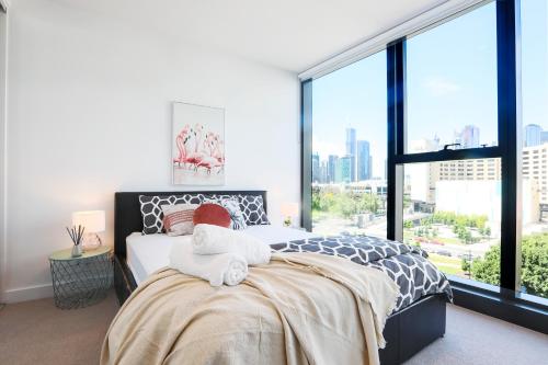 een slaapkamer met een bed en een groot raam bij KOZYGURU DOCKLANDS MODERN COZY 1 BED ROOM UNIT MELBOURNE VDO628 in Melbourne