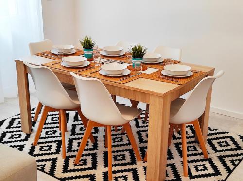 - une table à manger avec des chaises blanches et une table en bois dans l'établissement Maison avec jardin en centre ville - proche gare et circuit 24h du mans, au Mans