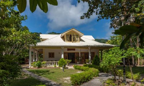 a home with a white house with trees at Kot Babi in La Digue