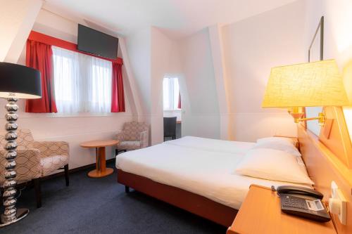 ein Hotelzimmer mit einem Bett und einem Schreibtisch mit einem Telefon in der Unterkunft Owl Hotel in Amsterdam