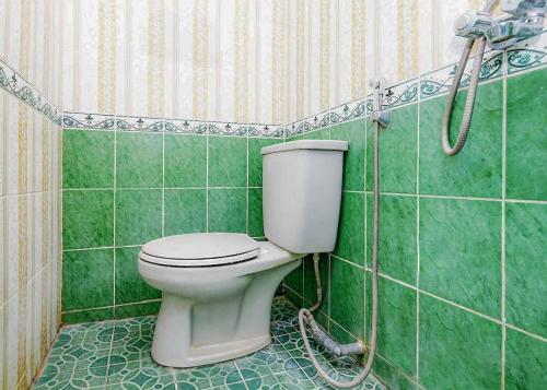 ein grünes Bad mit einem WC und einer Dusche in der Unterkunft Queen Asri Mitra RedDoorz in Kediri