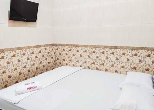 Bett in einem Zimmer mit einem TV an der Wand in der Unterkunft Queen Asri Mitra RedDoorz in Kediri