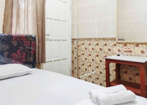 Schlafzimmer mit einem Bett, einem Waschbecken und einem Spiegel in der Unterkunft Queen Asri Mitra RedDoorz in Kediri