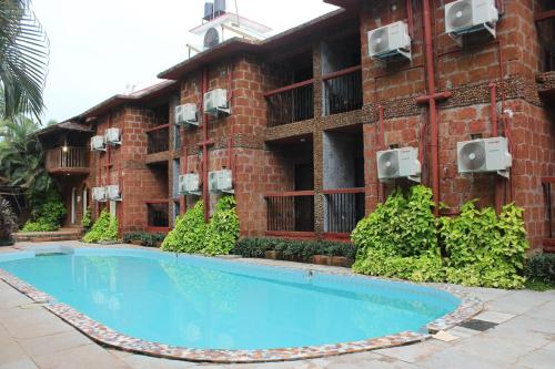 a brick building with a swimming pool in front of it at Sea Breeze Inn, Calangute Goa in Calangute