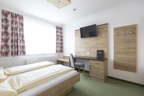 a bedroom with a bed and a desk and a tv at Hotel-Restaurant Planaihof in Schladming