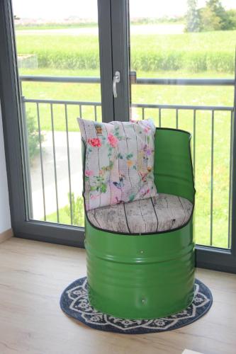 a green chair sitting in front of a window at Ferienwohnungen "Blumenwiese" in Dillingen an der Donau