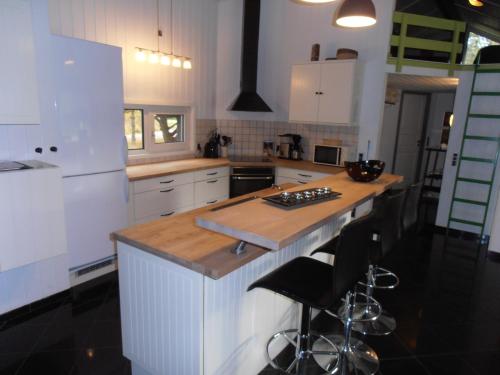 a kitchen with white cabinets and a wooden island with bar stools at Blåvand in Blåvand