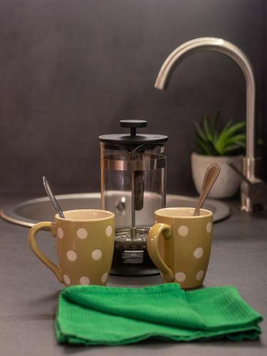 - deux tasses sur un comptoir de cuisine avec une cafetière dans l'établissement Chalet Alpine Rose, à Chamonix-Mont-Blanc