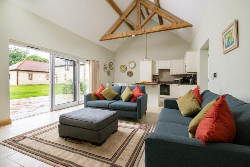 a living room with two blue couches and a kitchen at Barrow Hill Barns in Petersfield